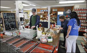 Robert Morrison rings up a sale for Rachel Parker, left, and Madhaui Raj at the co-op. Store owners are complaining that the city isn’t redirecting traffic for businesses.