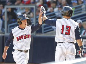 Toledo Mud Hens players Matt Young, left, and Jerad Head, (13) high five after Young scores on a hit by Ryan Strieby in the first inning.