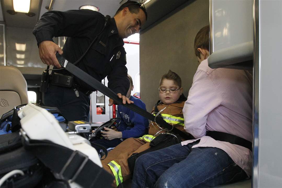 Perrysburg-Township-firefighter-Jim-Rodriguez-left-puts-a-seat-belt-on-Hunter-But