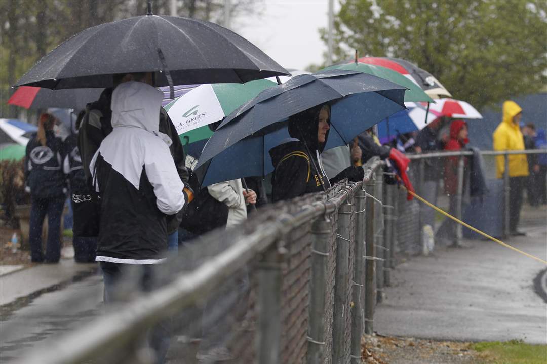 Spectators-armed-with-umbrellas-line-the-fence