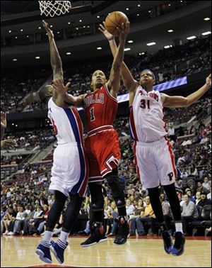 Bulls guard Derrick Rose (1) drives between Pistons defenders Rodney Stuckey, left, and Charlie Villanueva.