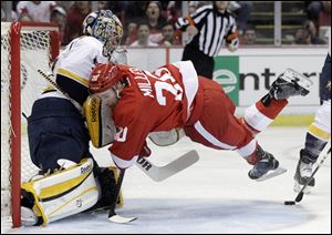 Left wing Drew Miller of the Red Wings rushes headlong into Predators goalie Pekka Rinne, left, during the first period of game 3 of first-round playoff action Sunday at Joe Louis Arena in Detroit.