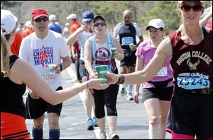 Runners pass a watering station during the Boston Marathon in Wellesley, Mass. on Monday. It was the second-slowest Boston race since 1985, as temperatures rising into the 80s slowed the leaders and may have convinced as many as 4,300 entrants to sit this one out.  