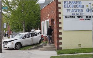 Stacey Turner, of Toledo, owner of Blessed Blossoms on Lagrange Street, stands on the flower shop's stoop and surveys the damage after a car struck the business Thursday morning.