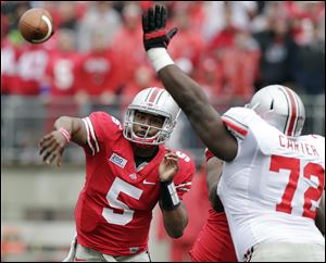 Ohio State quarterback Braxton Miller, left, throws a pass over lineman Chris Carter during their spring NCAA college football game today in Columbus.