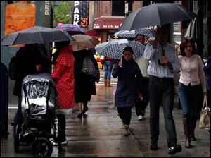 People walk with umbrellas in the rain along 9th Avenue in New York, Sunday.