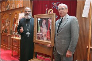 Father John Ragheb and Dr. Sabry Gohara, a retired surgeon and founding member of the local Coptic church, hold a portrait of Pope Shenouda, who died March 17.
