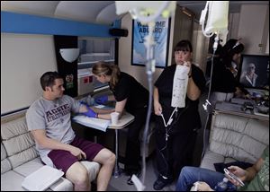 Emergency medical technician Debra Lund, right, prepares to hang an IV bag as co-worker Stacey Kreitlow, center, inserts an IV catheter into the arm of a patient in Las Vegas.