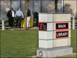 Toledo police investigate a body found Tuesday on a bench next to to the main branch of the Toledo-Lucas County Public Library in downtown Toledo.