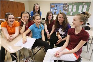 The seventh grade team from Byrnedale Elementary School in Toledo, that won the Blade's annual Student Stock Contest,  talks about how they picked their winning portfolio of stocks.  Team members from left are Emma Hansen, Marissa Hagen, Vanessa Skouroukos (back),  Emily Bettinger (with hand on stock page in Blade), Julie Bratton, Madison Huffman, and Kelsey Tiell. Not present for photo was Marisela Ruiz.