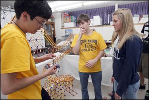 Mason High School students Scott Pomerville, left, Bret Konoff, and Moriah Foley talk about the roller coaster model they are creating to display at Cedar Point. The model will be on display at the Sandusky, Ohio, amusement park beginning May 14.