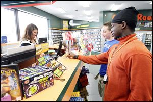 Kelly Delvaux, left, of the Jackman Road Family Video location, rents video games to Derek Roach, center, and Alontae Grimes.