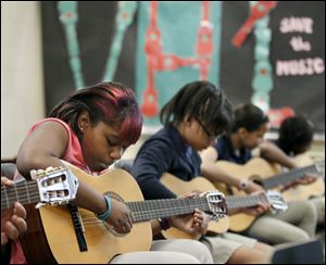 Sixth graders at Ella P. Stewart Academy for Girls, including Latyia Bourn, left, concentrate on learning to play the guitar. On Wednesday, they played for representatives of the VH1 Save the Music campaign.