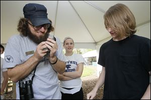 Ken Keffer. education director for the Black Swamp Bird Observatory, bands a gray xatbird as Whitmer High students Erica Wingate and Taylor Ellis watch. 