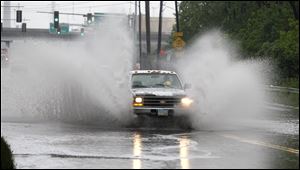 A truck splashes through standing water on Miami Street near I-75 in Toledo today.