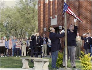 VFW honor guard members Clark Chafin, left, and Scott Goeckerman lower the flag at Walbridge Elementary during
a farewell ceremony as alumni, staff, and students look on. The ceremony Tuesday was part of an open house at which the public could learn more about, and tour, the building. It will be closed at the end of this school year. 