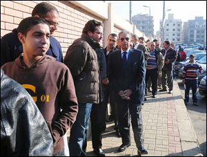 Egyptian presidential hopeful Amr Moussa, center, waits outside a polling station before voting on the first day of parliamentary elections in Cairo, Egypt.