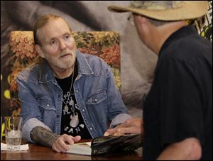 Gregg Allman, left, founding member of The Allman Brothers Band, talks with a fan as he signs copies of his autobiography 
