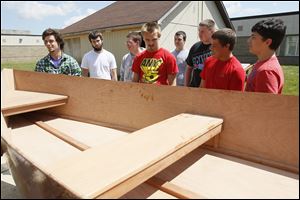 Aaron Zimmerman, left, and his classmates inspect the boat he made for his cabinetry class. He worked on the project for two trimesters and hopes to have it completed with oarlocks and handrails before his June 2 graduation.