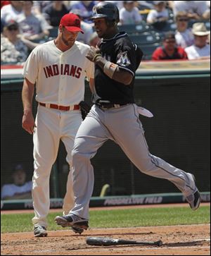 The Marlins' Hanley Ramirez, right, crosses the plate to score off teammate Greg Dobbs' double to center in the third inning against the Cleveland Indians. Indians starting pitcher Derek Lowe, left, looks on.