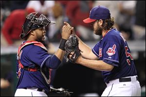 The Indians' Carlos Santana, left, congratulates pitcher Chris Perez at the end of the game as Perez picked up the save. Perez survived a shaky ninth in which the Tigers put runners on first and third.