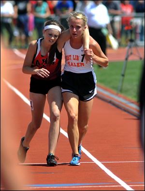 Meghan Vogel, right, helps Arden McMath to the finish line Saturday in Columbus in the 3,200-meter run.