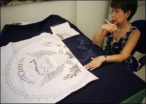 Hue Nguyen draws the presidential pattern for the fabric workers on material used in the embroidery process.
