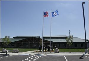 Flags are raised before the opening of the U.S. Customs and Border Protection facility near Port Clinton. The large building includes an indoor parking garage.