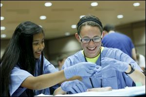 Rebeckah Jo Tilley and Andrea Aeschliman, both 14, work together to suture a pig’s foot during the 14th annual CampMed program at  the University of Toledo Medical Center, the former Medical College of Ohio.