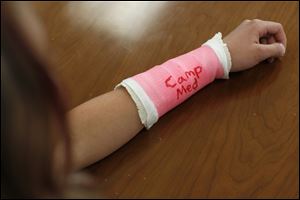 Samantha Deanda, 14, lets the ink dry on her fake cast during the CampMed program. The students were among 39 high school freshmen who participated in a two-day camp through the UT and Ohio Area Health Education Center; it ended Friday. UT medical students were camp counselors.