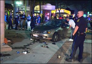 Emergency personnel surround the car that a 63-year-old woman drove into Lima's town square during a music event. Police withheld her identity Saturday night.