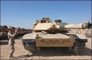 A U.S. Army sergeant directs an M1A1 Abrams heavy-battle tank at Camp New York in the Kuwaiti desert in 2002 during the buildup before the Iraq war. 