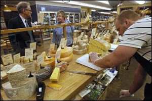 Customers Peter Price and Mary Kinley wait as John Mueller slices their cheese orders at Morgan & York wine and cheese store in Ann Arbor, Mich.