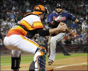 Houston Astros catcher Chris Snyder, left, waits with the ball to keep Cleveland Indians' Carlos Santana from scoring in the seventh inning of a baseball game Friday, in Houston. The Indians won 2-0.