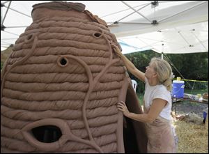 Ceramic artist Laurie Spencer touches up some of the coils before wetting down and covering the 8-foot beehive structure. 