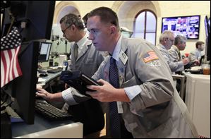 Trader Justin Finn, center, check a screen in his booth on the floor of the New York Stock Exchange Monday.