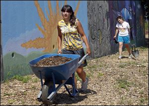 Samantha Koch, left, and Katie Rosenblatt work in the Manos Community Garden at Jackson Boulevard and 14th Street in Toledo's UpTown District. 