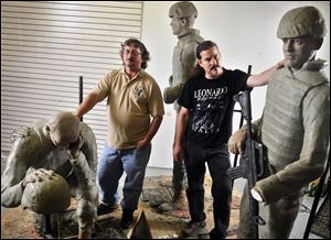 Joe Levandoski, left, looks on as Grand Rapids artist Mic Carlson  pauses during his work on the sculpture. It is to commemorate lives lost in battles in Afghanistan and Iraq since the Sept. 11, 2001, attacks.