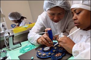  Tanyapat Jakaew, a trainer from Thailand, shows Judith Walker of Detroit how to assemble a Shinola-brand watch at a new manufacturing site in Detroit.