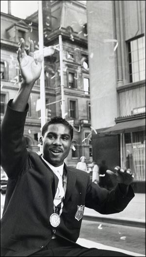Wilbert ‘Skeeter’ McClure wears his gold medal and waves to the
crowd in downtown Toledo during a ticker-tape parade.