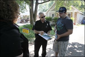 Deputy Lucas County Dog Warden Walt Raftery, center, issues citations for unlicensed dogs to Jason Kelley on Thursday, June 21, on Curson Drive in Toledo. Looking on is Lucas county Dog Warden Julie Lyle. Three of the family's dogs had escaped through a hole in the fence and were roaming the neighborhood, causing a neighbor to call the Dog Warden's office. The citations will be rescinded if the family gets the dogs licensed.