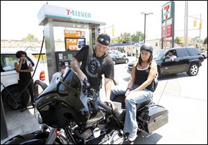Matt Zdybek fills his motorcycle with $3.399-per-gallon gasoline as Holly Lambrecht waits on the back at a 7-Eleven station on Lewis Avenue. After a trip out of town, he was disappointed to see how much prices had risen when he returned. Prices had been falling earlier.