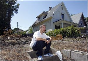 Richard Meeker sits near Jenny Fowler's home, right, and the area where a house next door burned to the ground, last week. Meeker saw the flames and pounded on the door to make sure that Fowler and her family got out of the house safely.