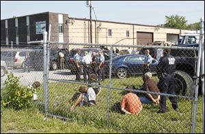 Authorities today keep people in handcuffs on the property of a garage on Angola Street in South Toledo.