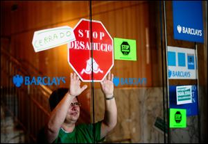 A woman protests against evictions and banks Thursday inside of a Barclays bank office in Barcelona, Spain. An elected member of the British Parliament, Steve Baker is part of a growing rank of furious politicians increasing the pressure on Prime Minister David Cameron to hold a national referendum on a once unthinkable notion here: Leaving the European Union.