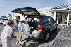 Gary Sahadi loads clothes into the car of customer Nan Bedee-Gilley at Colonial Cleaners on Lewis Avenue. The business was founded by his father, Phil, after he returned to Toledo from military service in World War II.