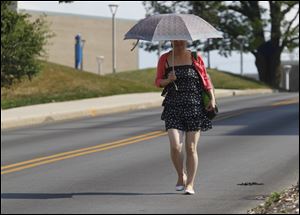University of Toledo student Raio Sho tries to shield herself from the sun while walking on campus. Temperatures are expected to reach the low 90s today.