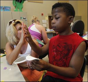 Special education teacher Lisa Elam high-fives Michael Carter, 13, after he made a visor during summer camp at Robinson Junior High School.