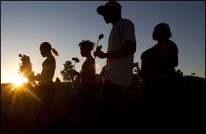 From left, Tylecia Amos, 14, Shatyra Amos, 15, Michael Walker, 17, and Mykia Walker, 16, carry flowers to lay at a makeshift memorial across the street from the Century Theater parking lot in Aurora, Colo.