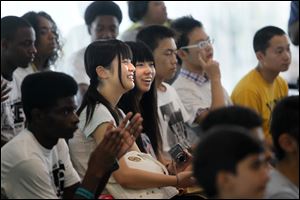 Kanako Ushikubo and Haruka Miyata, center, watch other international students help with the glass-blowing demonstration at the Toledo Museum of Art's Glass Pavilion.